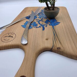 A cutting board with wine leaves engraves filled with blue epoxy resin