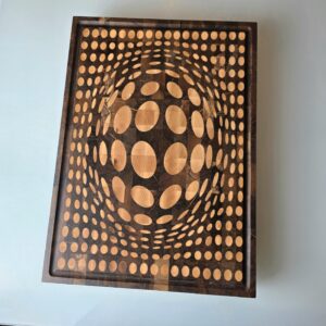 Top view of 3D optical illusion cutting board made from Romanian Walnut and Maple. Geometric vortex pattern with persimmon fruit for scale. End-grain butcher block construction.