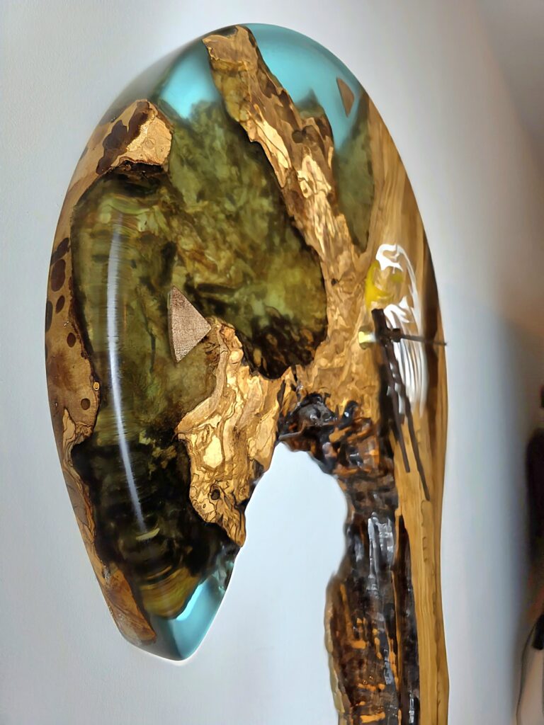 Side profile of 3.3cm thick live edge wall clock. Shows the depth of the teal resin and the high-gloss finish on the olive wood burl.