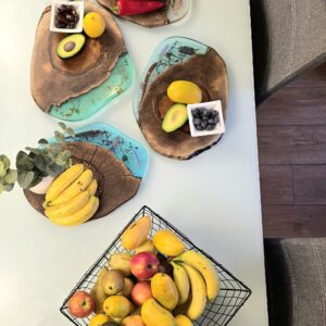 4 Live edge wood cheese board with turquoise, clear, blue and green resin detailing, being used to serve appetizers.