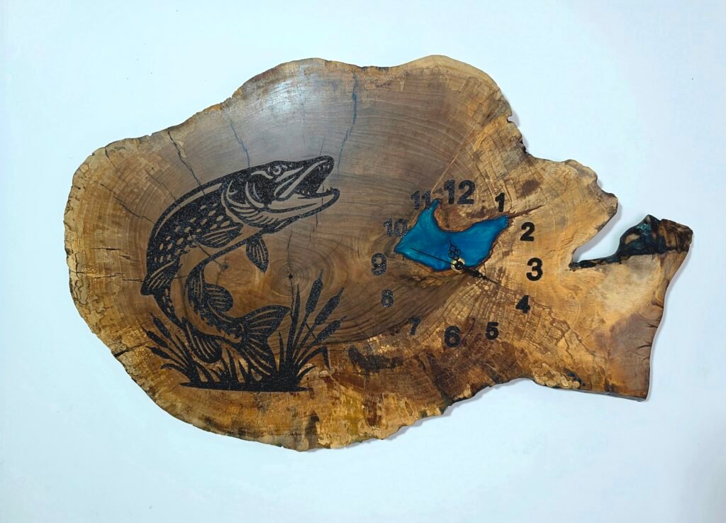 Wooden tree-slice clock with black fish engraving and blue accents near the center/5 o'clock area (numbers around the edge)
