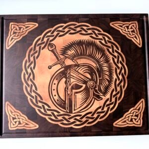A rectangular end-grain wooden cutting board featuring a detailed inlaid design of a Spartan walnut cutting board with a sword and shield, encircled by a Celtic knot border with triangular corner accents.