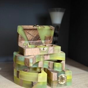 A stack of handmade wooden and translucent lime green resin jewelry boxes with gold-toned brass hardware, with the top box open.